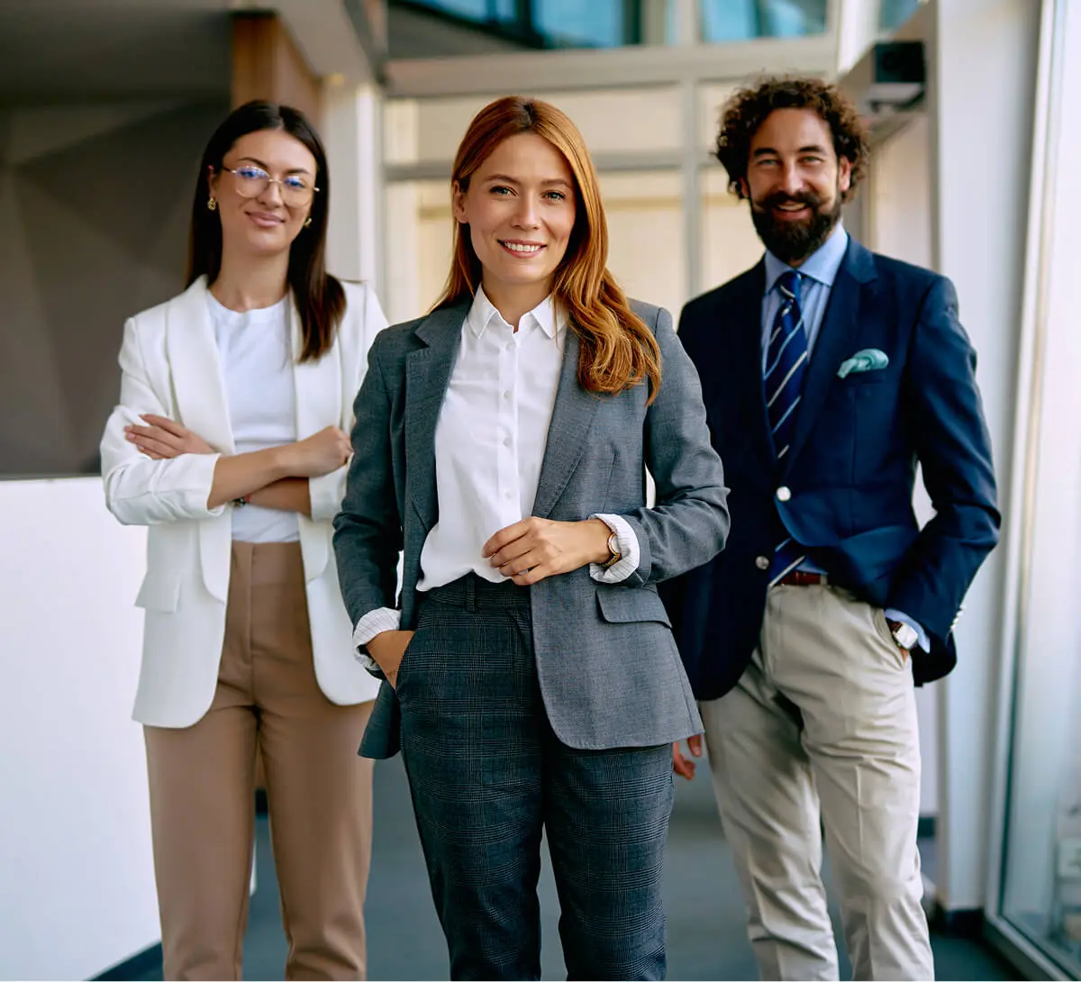 Three professionals smiling in a modern office.