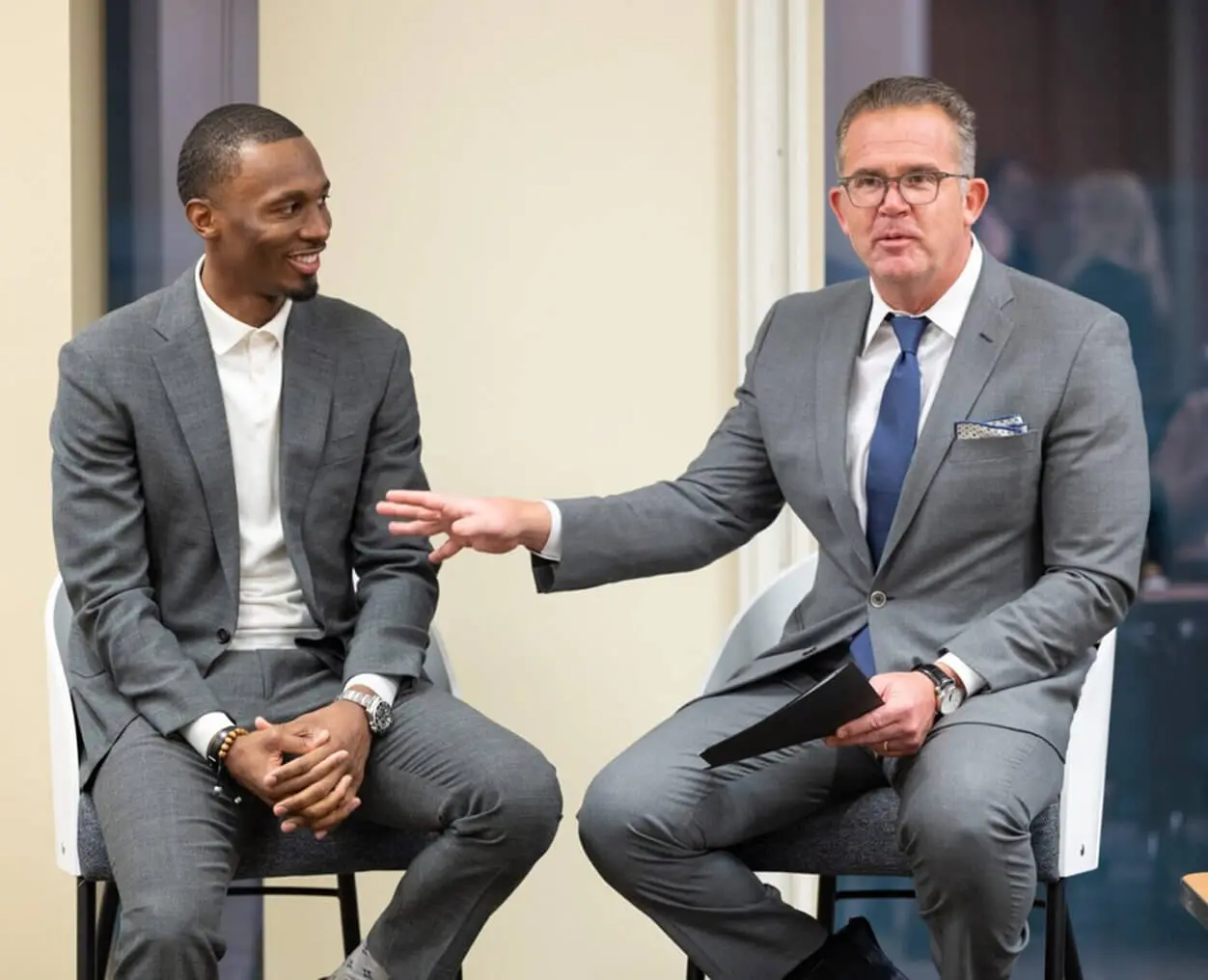 Two men in suits having a discussion.
