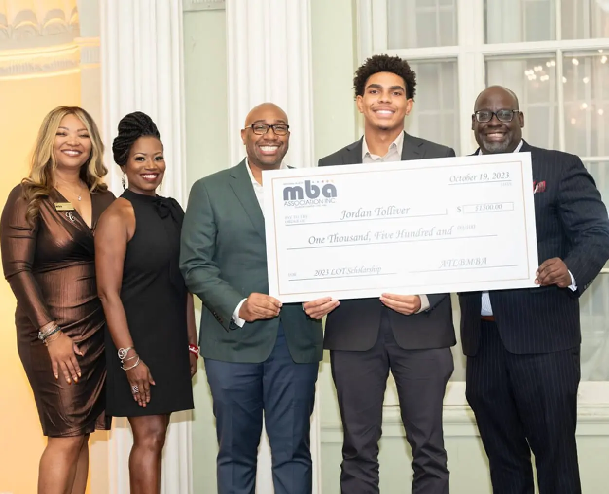 Group holding large check, smiling together.