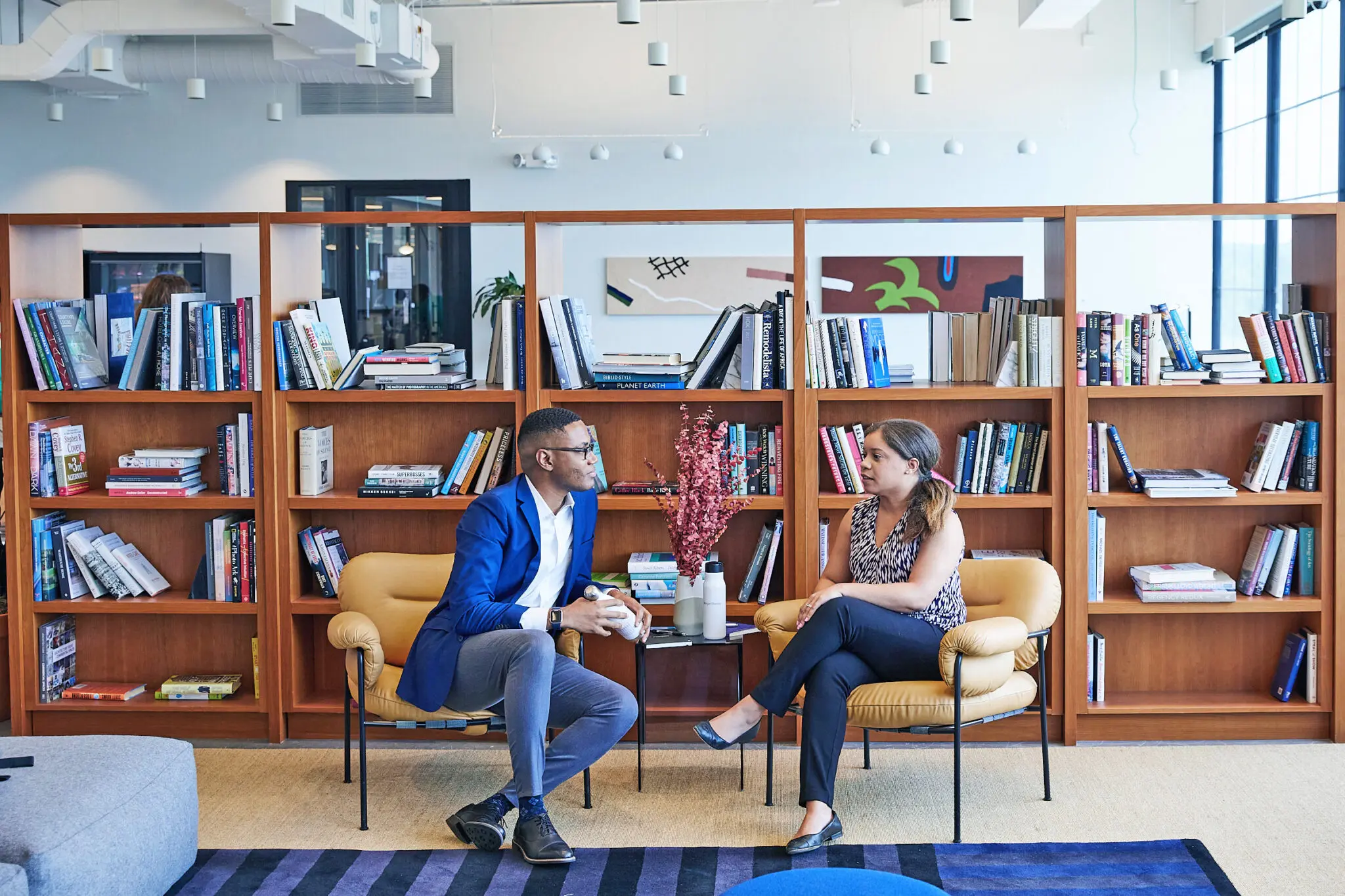 Two people conversing in a modern library.