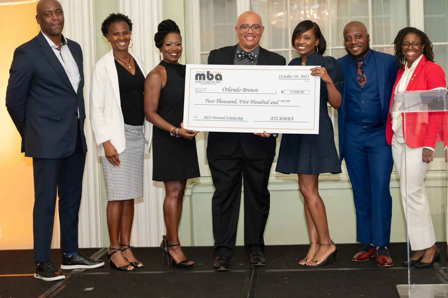 Group holding a large ceremonial check indoors.
