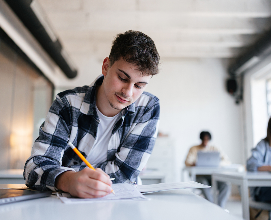 Student writing at a desk in classroom.