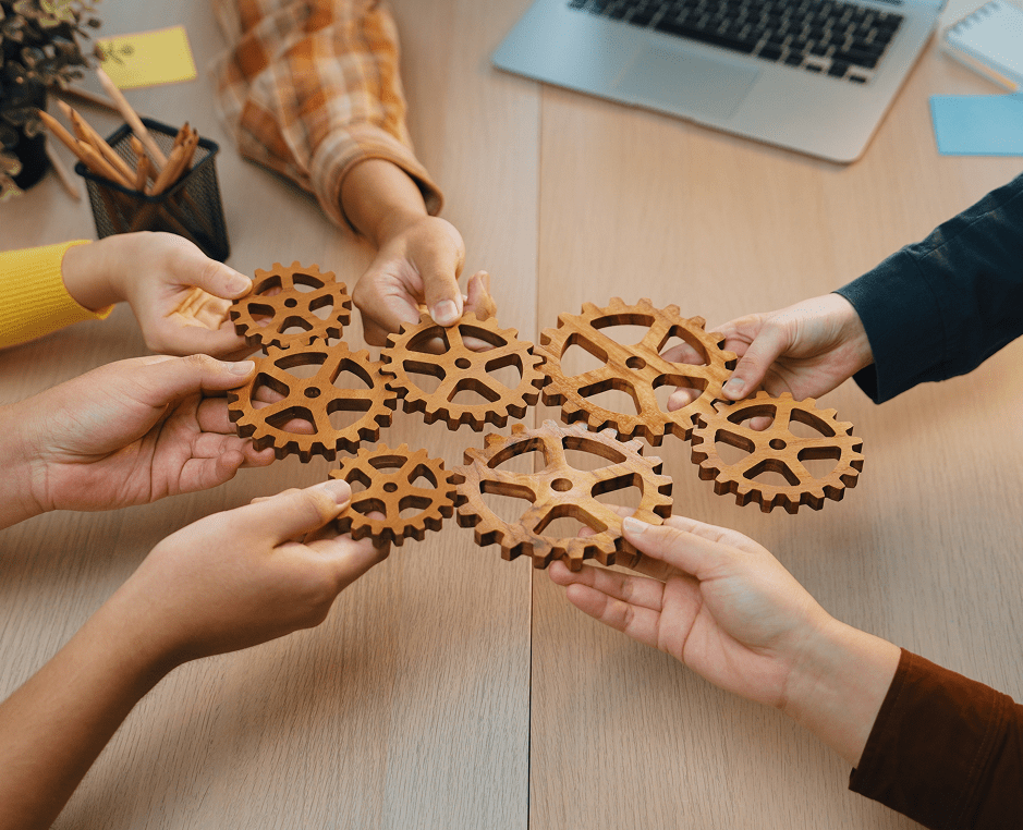 Hands holding wooden interlocking gears together.