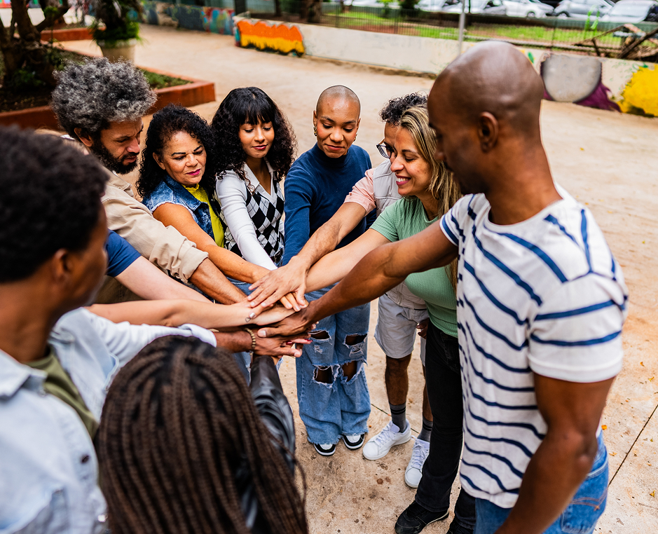 Group of people joining hands outdoors.