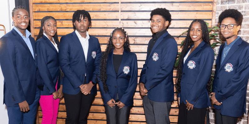 Group of people in matching navy blazers.